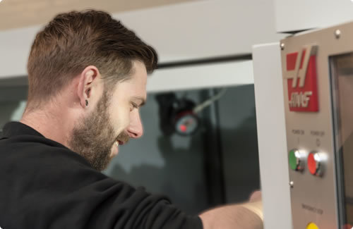 Techniker arbeitet an einer CNC-Maschine von Haas in moderner Produktionsumgebung