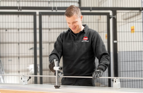 THN employee measures a precision shaft with precision equipment in a workshop.