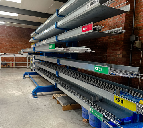 Magazijnstelling met assen in voorraad, gelabeld per staaltype zoals CF53 en X90