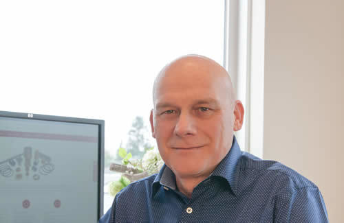 Man met blauw overhemd bij computerscherm, klantenservicekantoor met daglicht