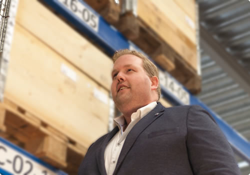 Commercieel directeur van THN in magazijn tussen hoge stellingen met houten kratten