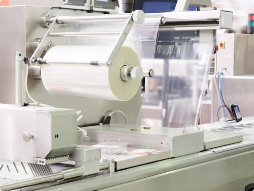 Industriële verpakkingsmachine met transparante folierol in productielijn