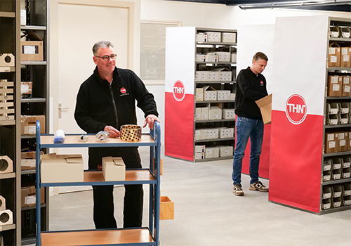 Magazijnmedewerkers van THN verzamelen onderdelen tussen rekken en stellingen in het magazijn
